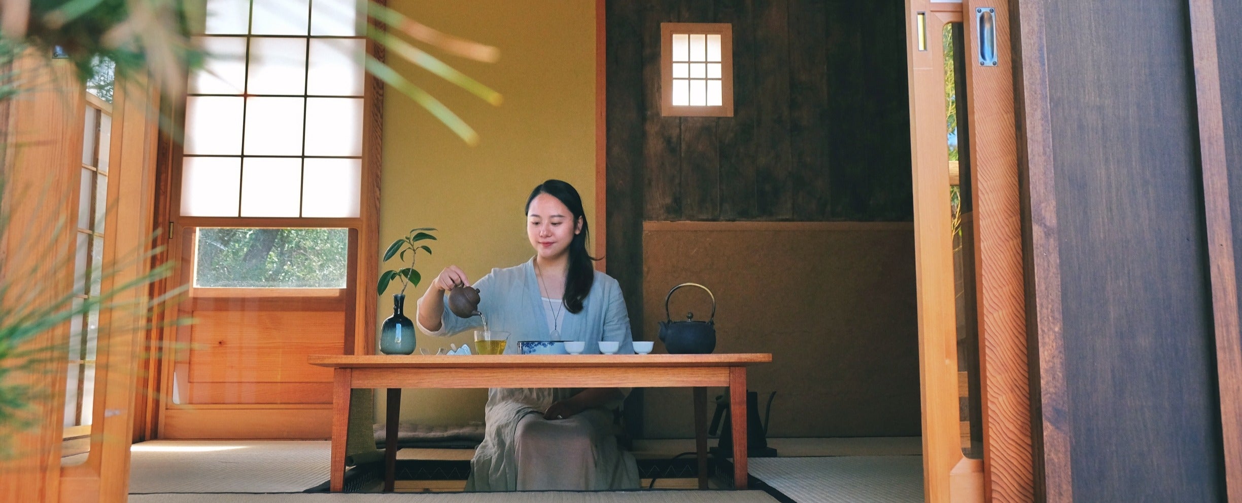 Woman sitting at a wooden table pouring tea