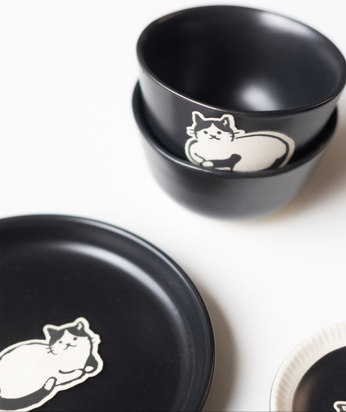 Two black cat cups stacked, cream cat motif and cream foot