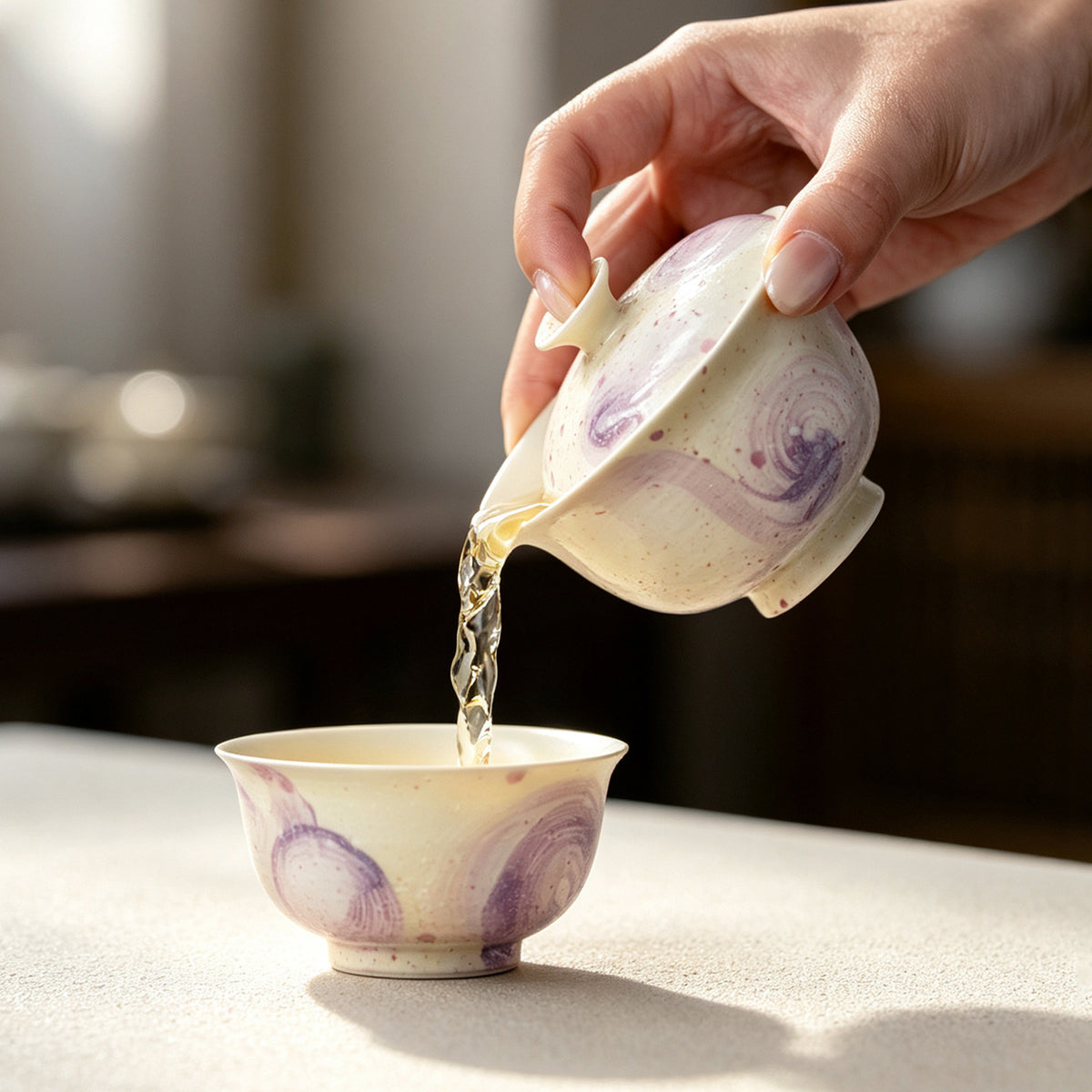Pouring tea from the purple swirl gaiwan into the matching cup