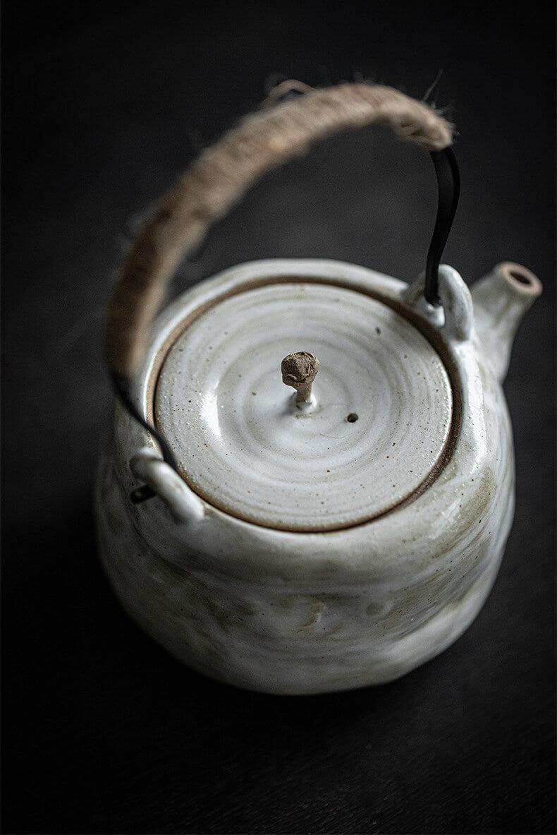 White ceramic teapot with a textured surface on a dark background