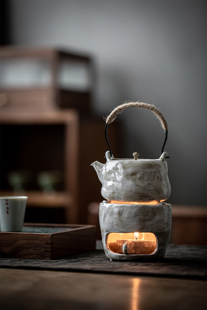 Ceramic teapot on a warmer with a blurred background
