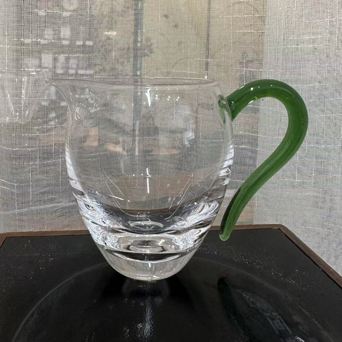 Thick-base glass gongdao cup with solid green glass handle, photographed in store