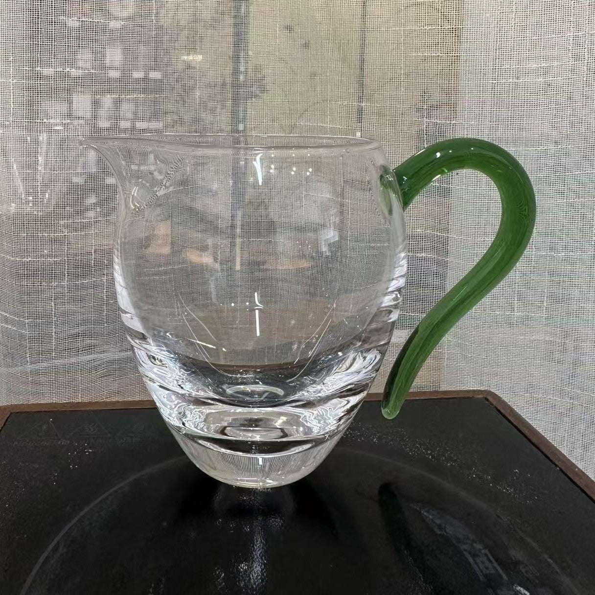 Thick-base glass gongdao cup with solid green glass handle, photographed in store