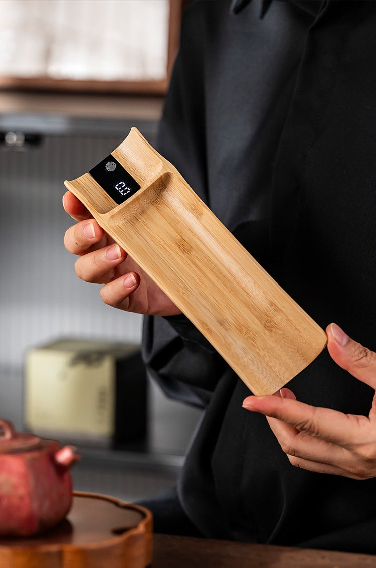 Bamboo tea scale held in both hands, showing the curved trough and length