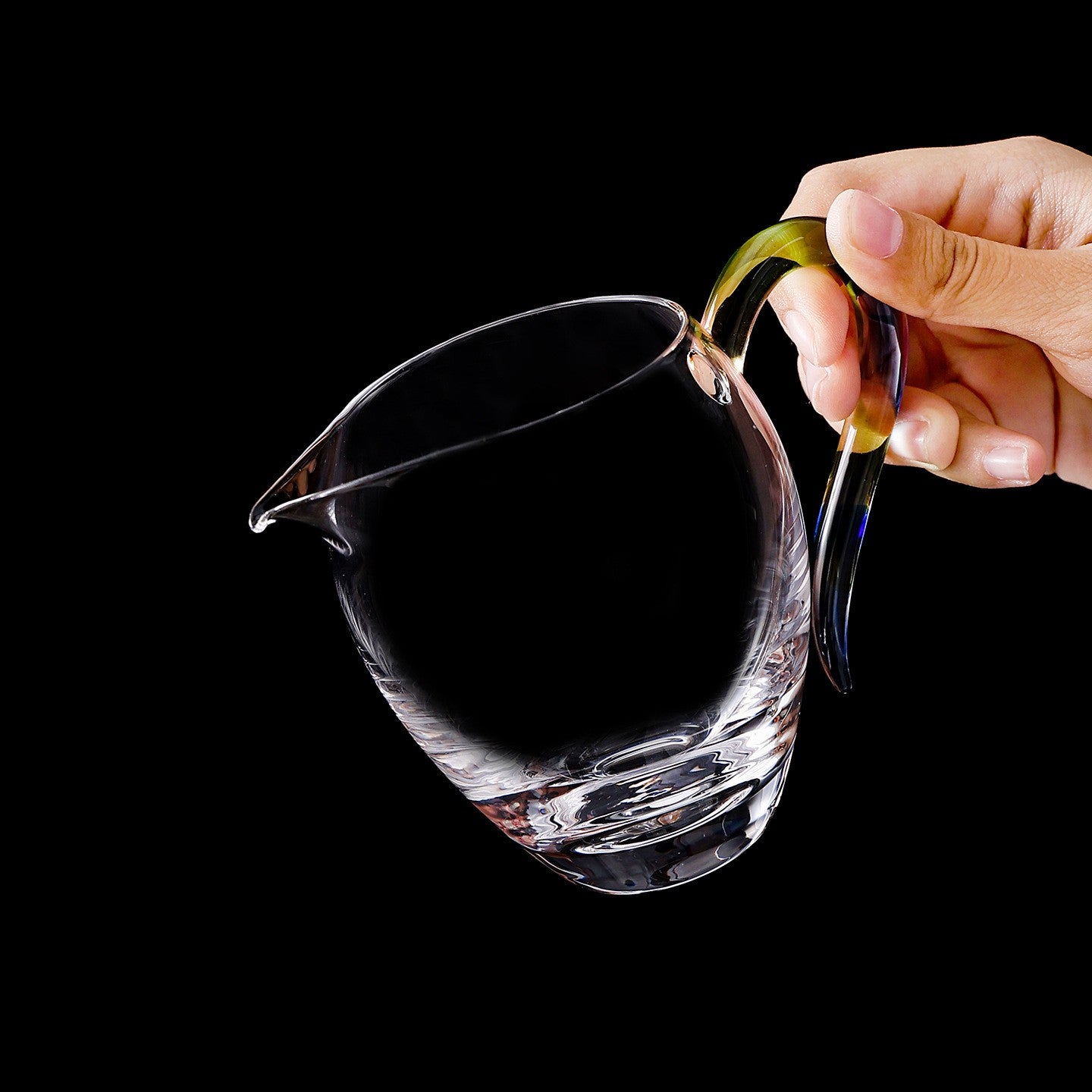 Hand holding the thick-base glass gongdao cup by its Rainbow handle, tilted to pour
