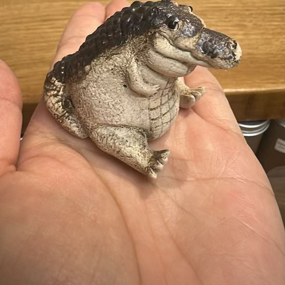 Little Crocodile tea pet sitting in an open palm for scale