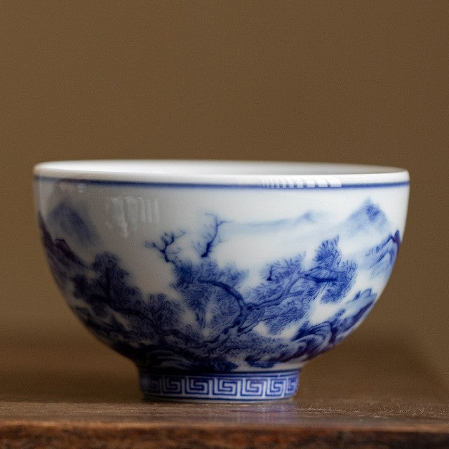 Matching cup in the landscape pattern, blue and white porcelain, on a wooden table