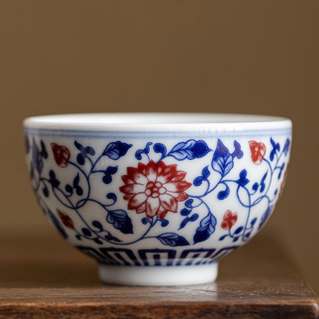 Matching cup in the lotus pattern with underglaze red flowers, on a wooden table