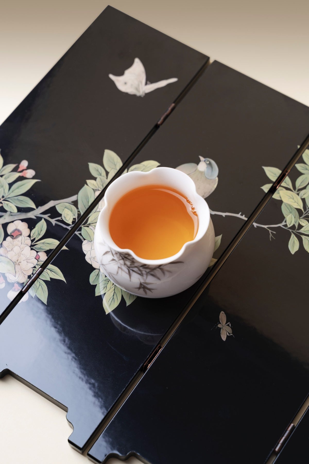 Black Bamboo mini folding screen, reverse blossom side, lying flat with a white cup of tea on it