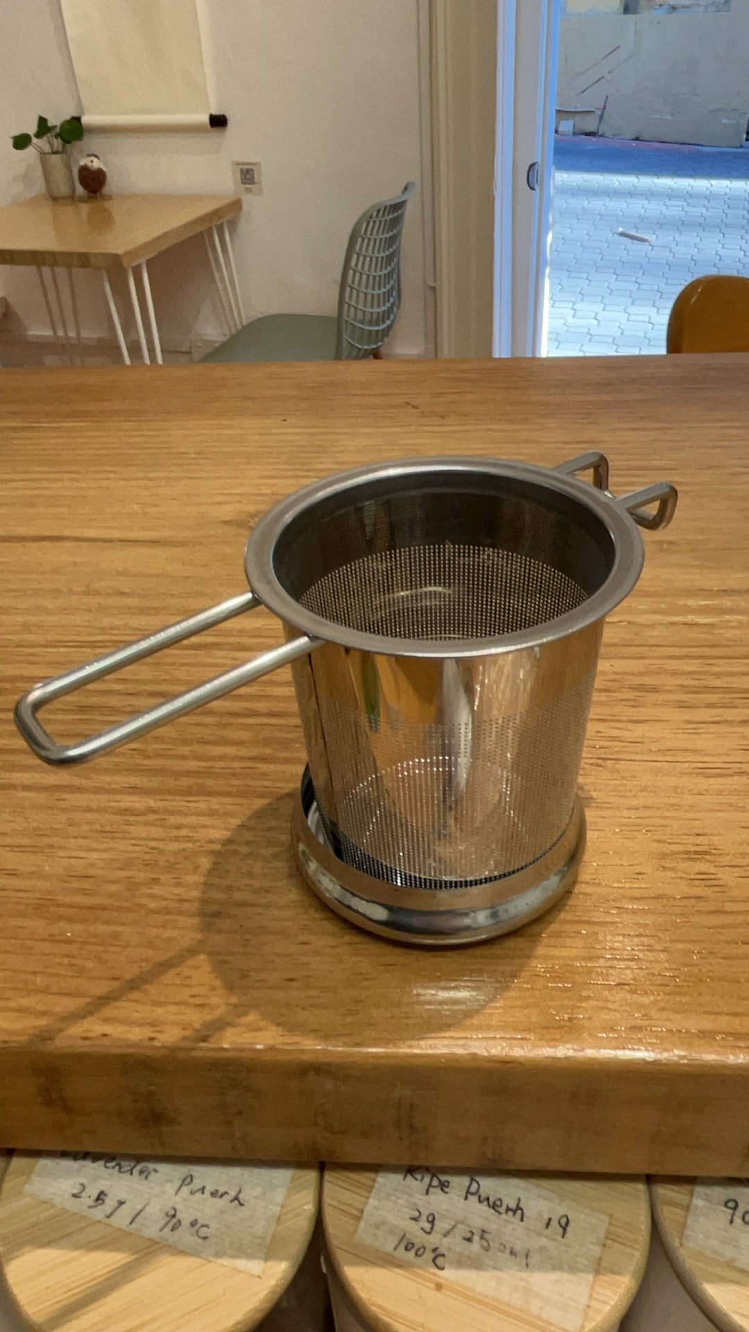 Stainless steel tea infuser basket sitting on a timber counter in the Hobart tea bar