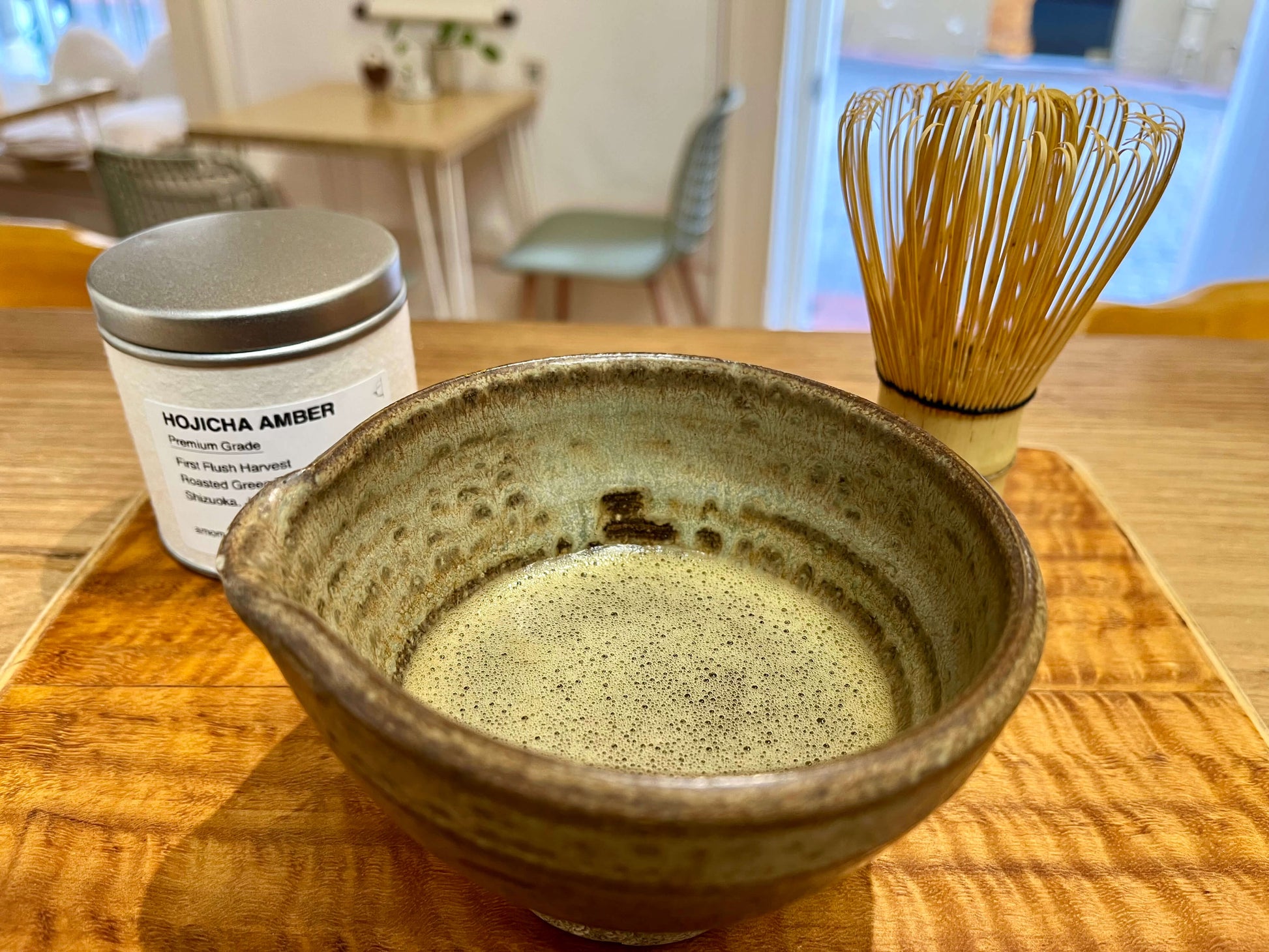 Whisked hojicha in a chawan with Hojicha Powder Amber tin and bamboo whisk