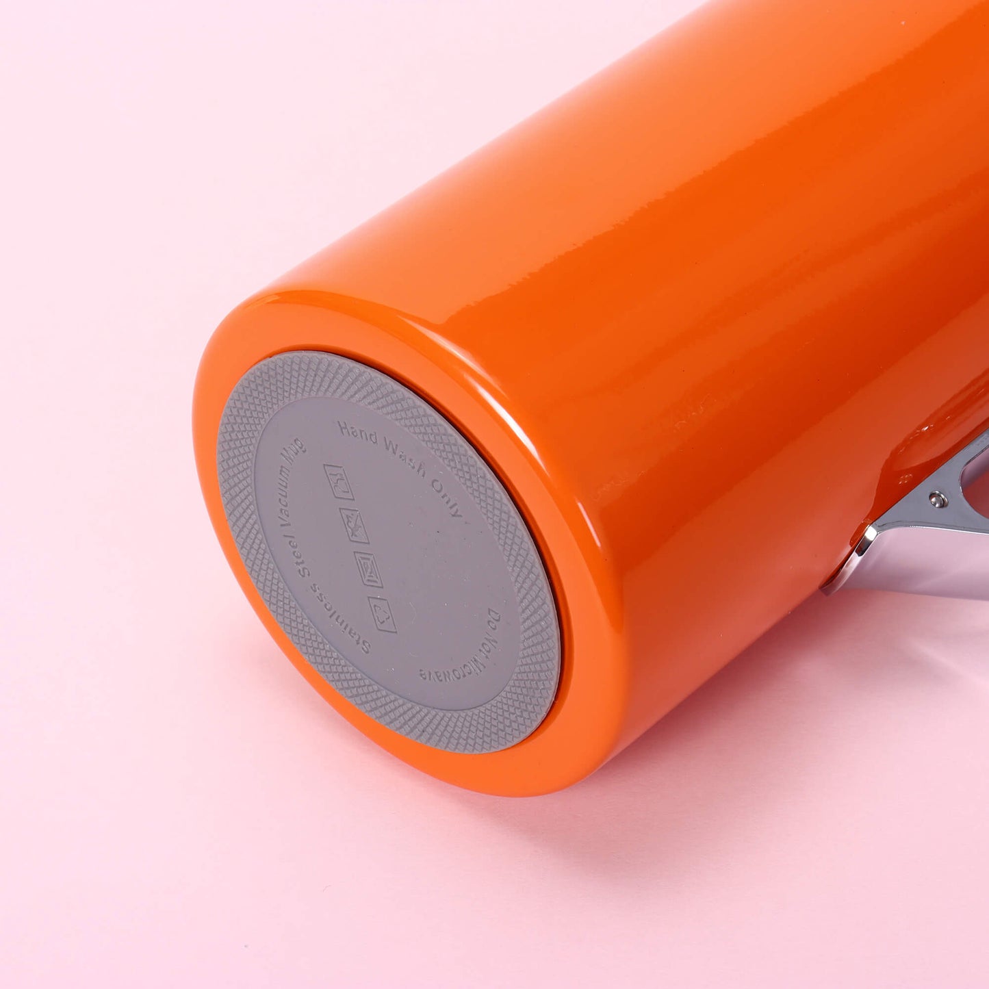 Orange water bottle with gray cap on a pink background