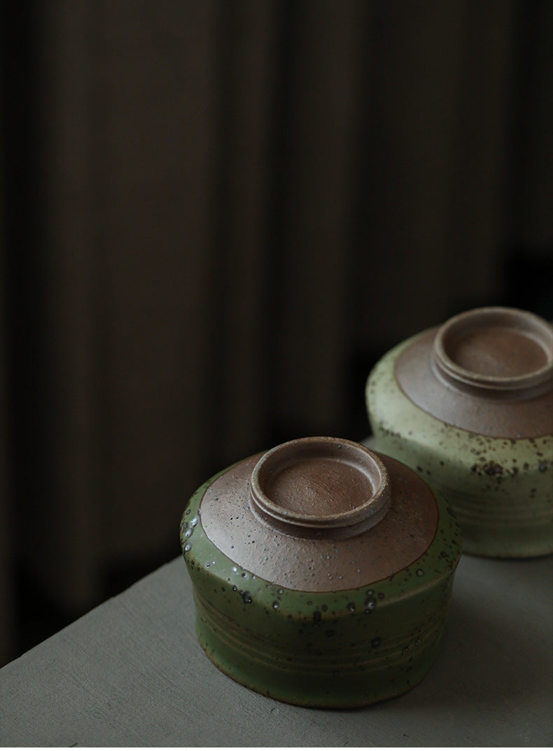 Two ceramic Matcha bowl with green and brown glaze on a dark background upside down