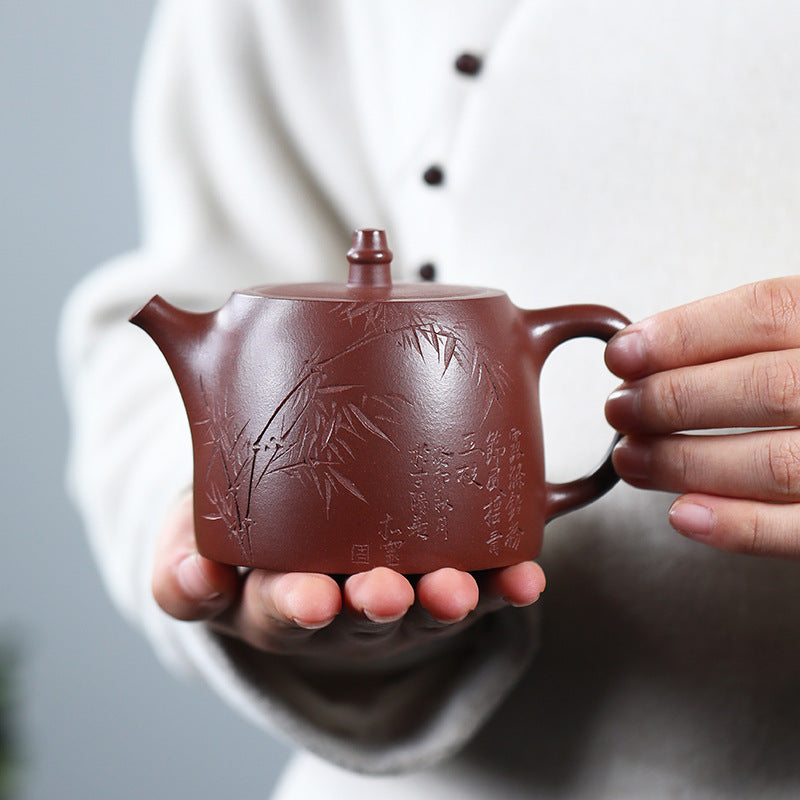 Hand-carved bamboo on a Yixing purple clay Handuo teapot, held in hand