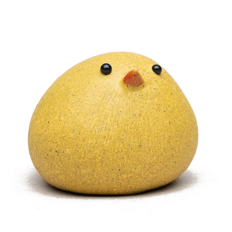 Yellow bird-shaped object with black eyes and a red beak on a white background