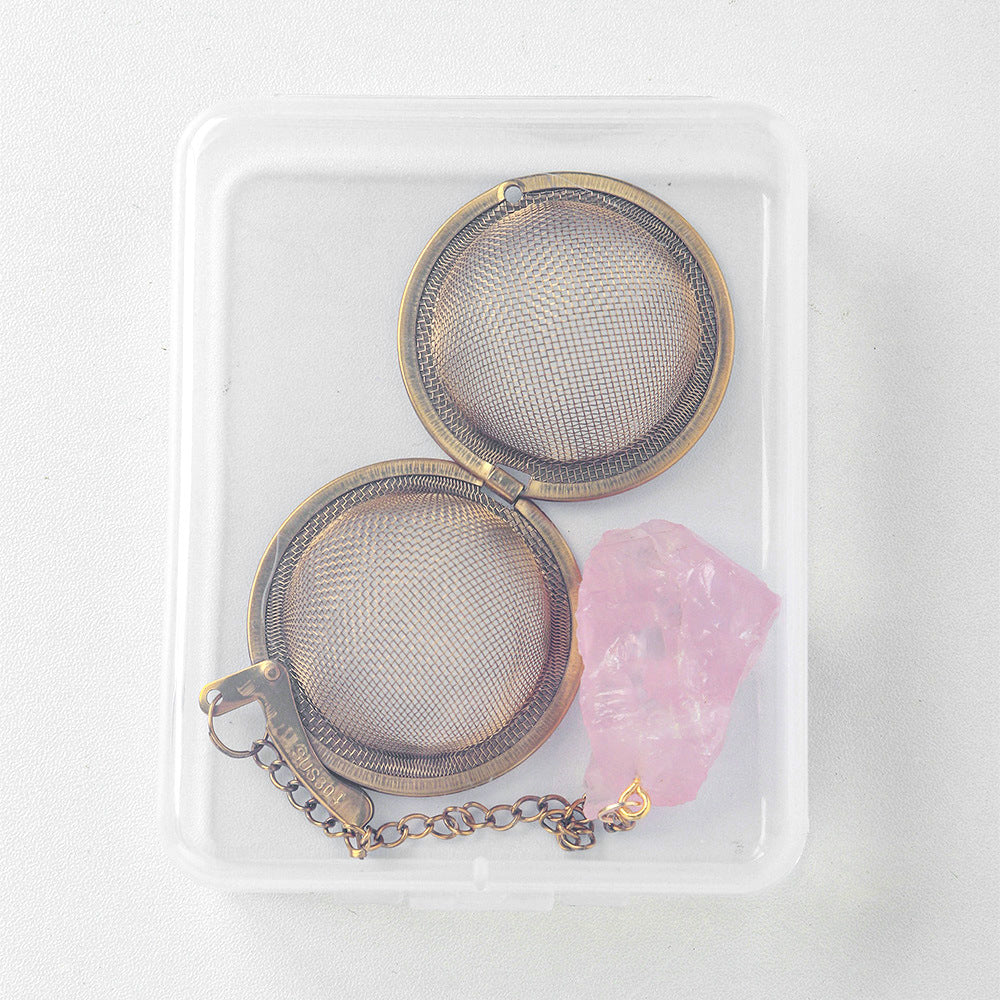Two stainless steel mesh tea infuser balls with a raw rose quartz stone, in a clear storage box