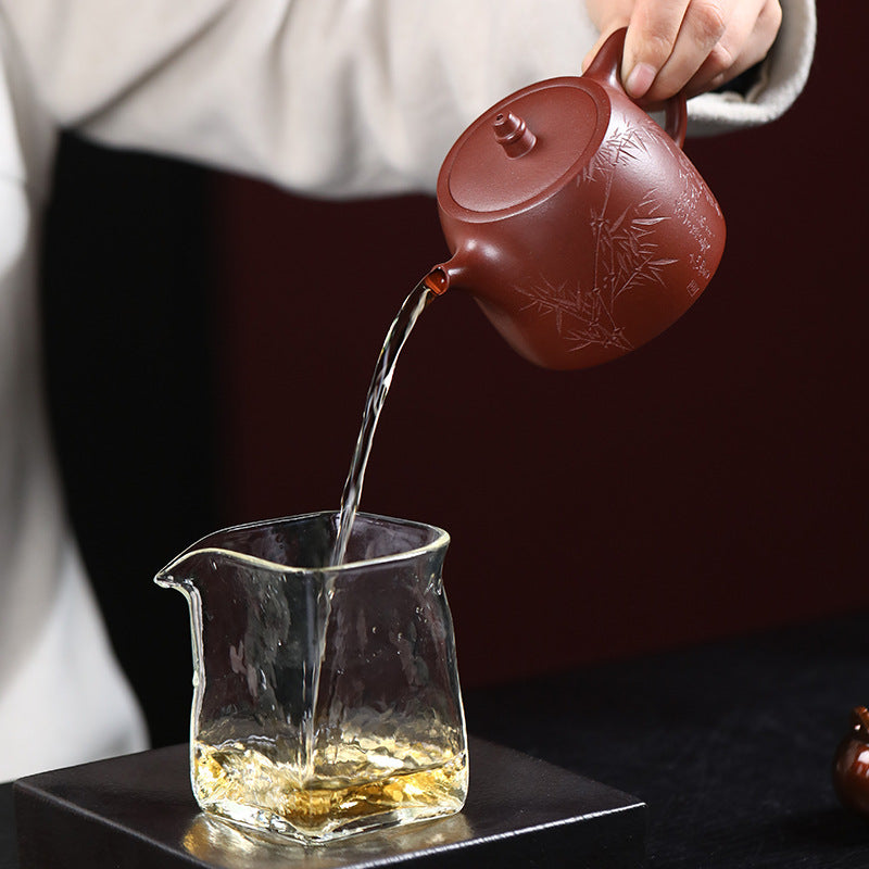 Bamboo Yixing zisha teapot pouring tea into a glass fair cup