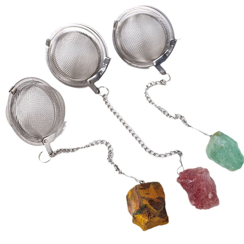 Close-up of two mesh tea infuser balls with amber and pink raw crystal counterweights