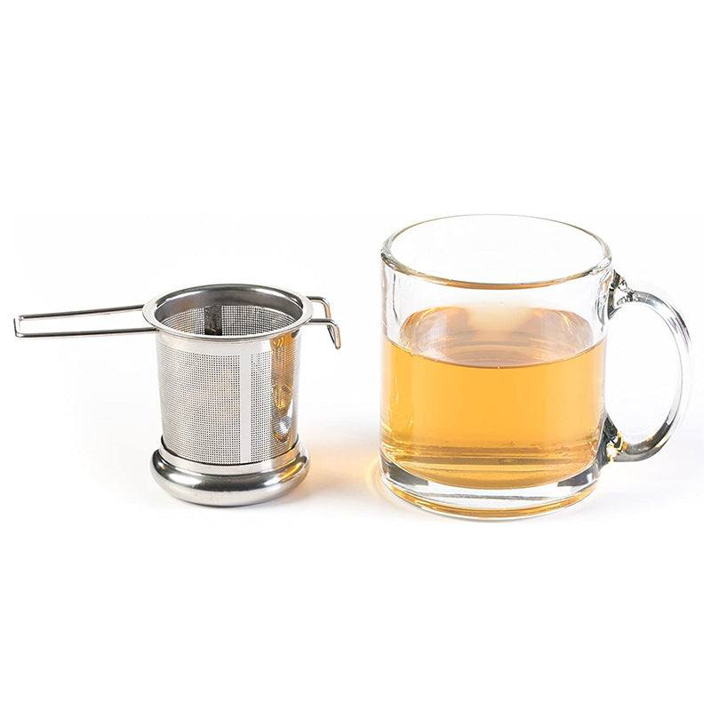 Tea infuser basket beside a glass mug of brewed tea