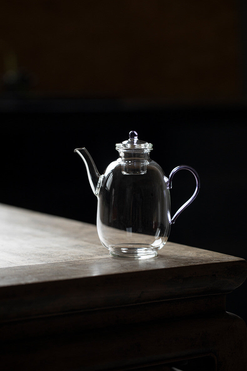 Clear glass teapot on a wooden surface with a dark background