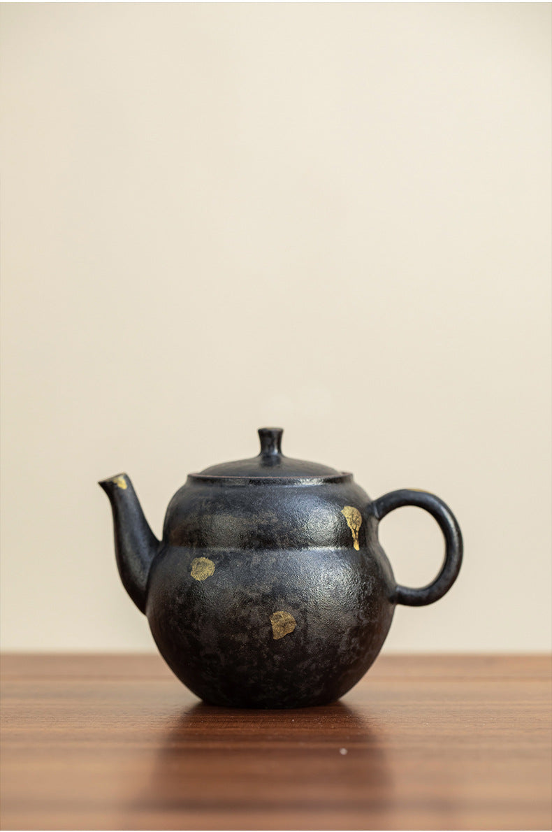 Black gourd-shaped stoneware teapot on a timber table