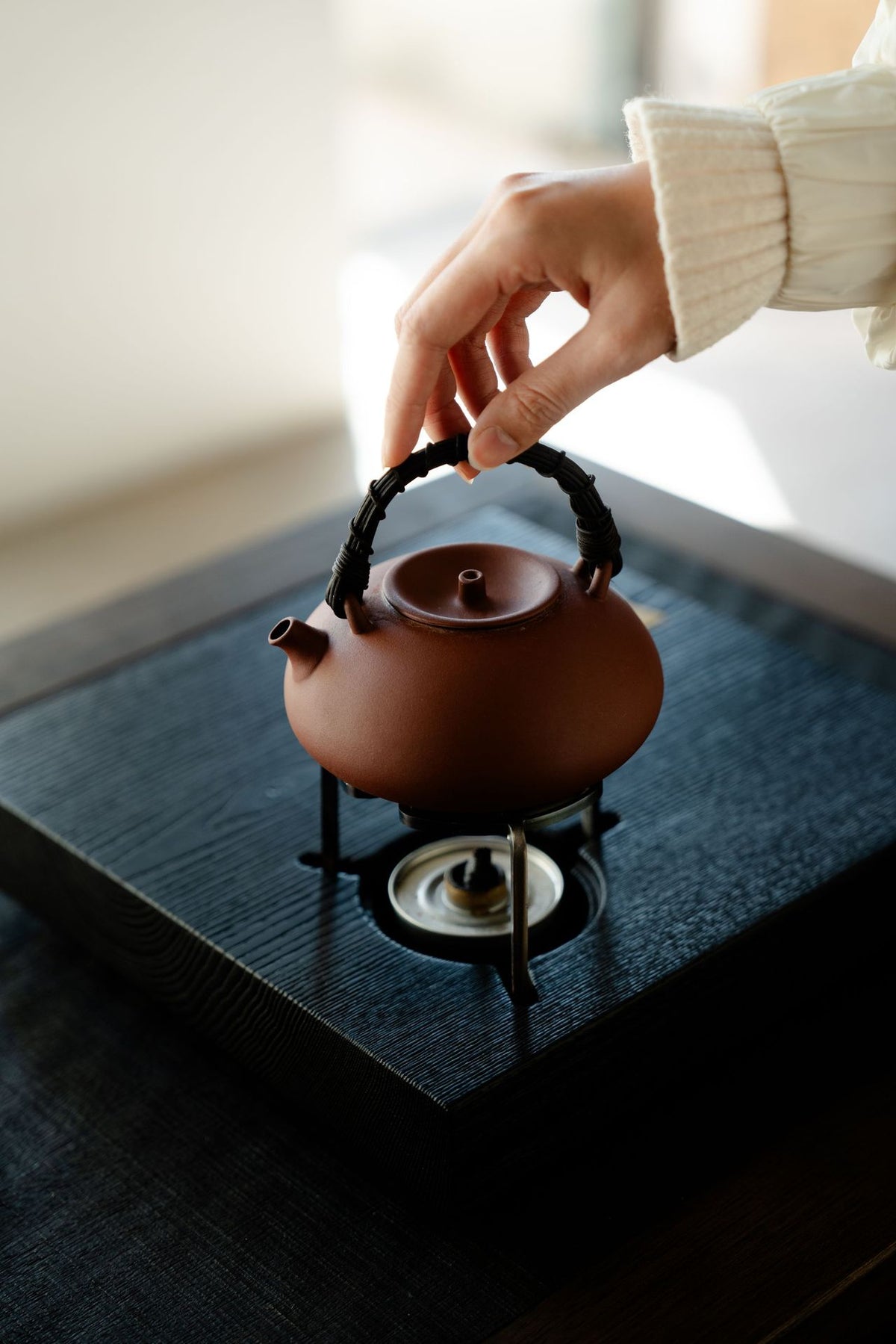 Red clay boiling teapot sitting on a small alcohol burner stand