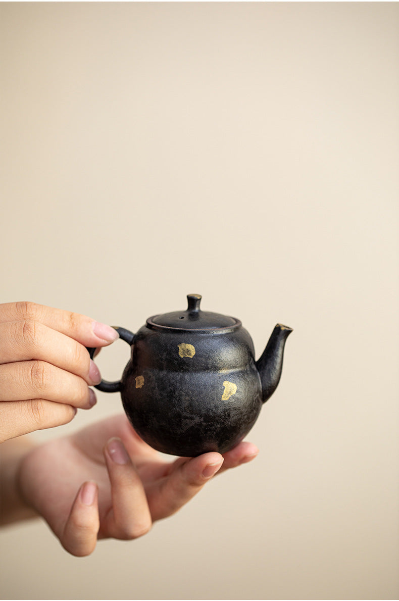 Black clay gourd teapot held in hand to show its size