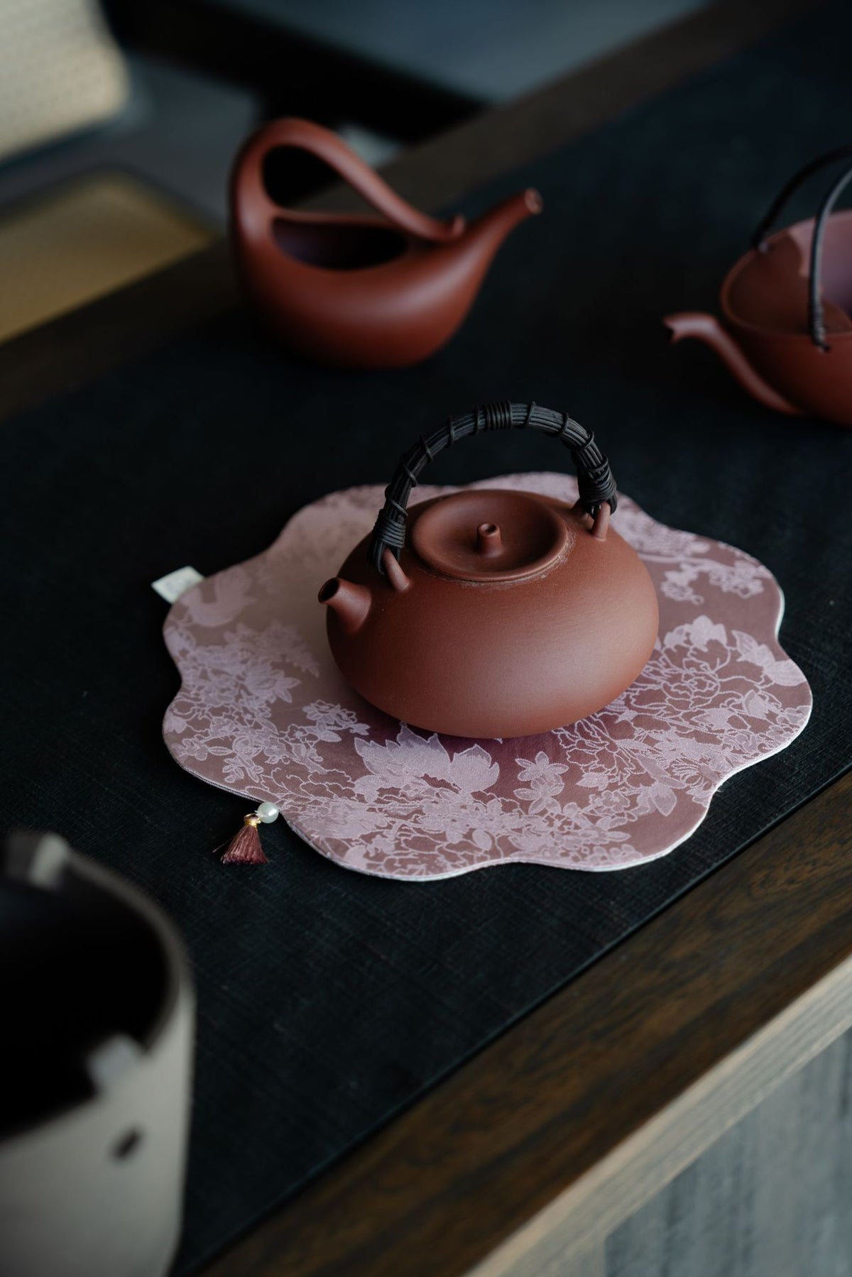 Red clay boiling teapot on a patterned mat on a tea table