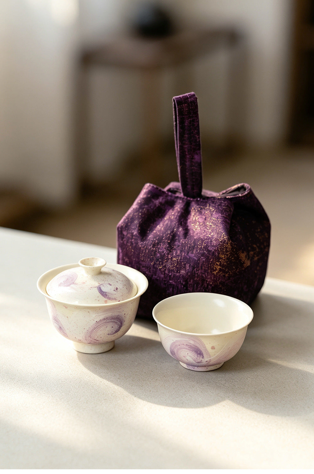 Purple swirl porcelain gaiwan and cup beside the closed travel pouch