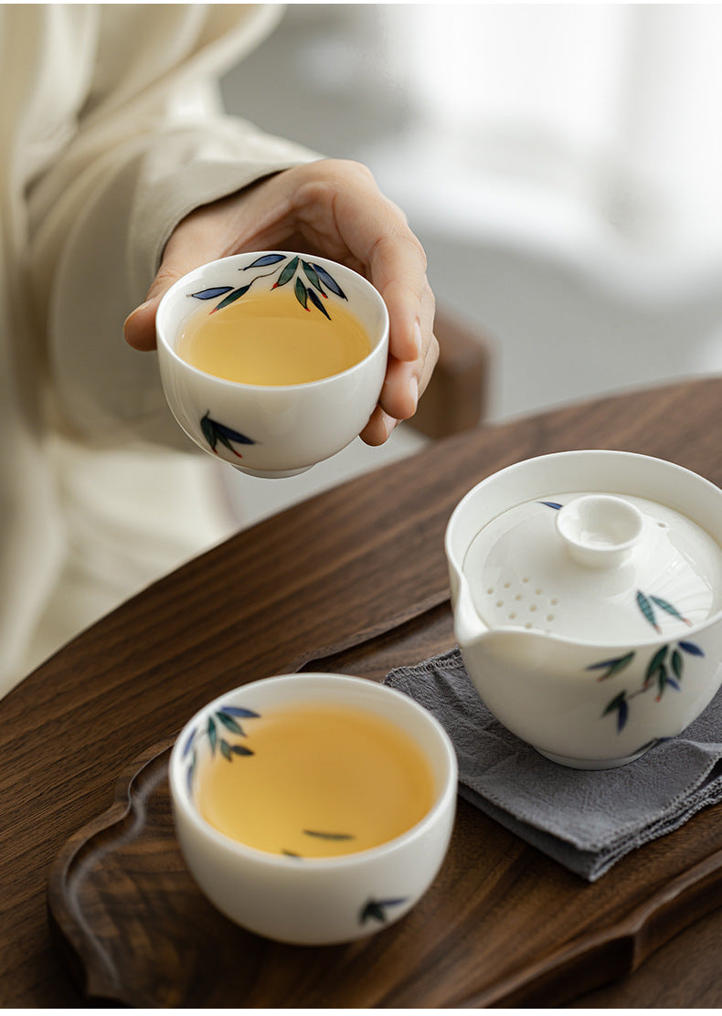 Person holding a teacup with tea on a wooden table