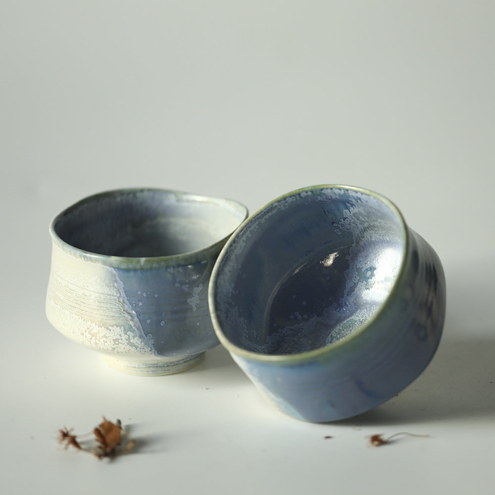 Two blue ceramic matcha bowls on a light grey background