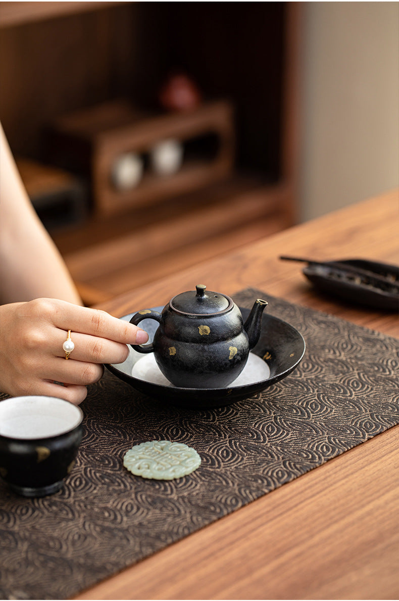 Black clay gourd teapot on the matching gold fleck teapot stand
