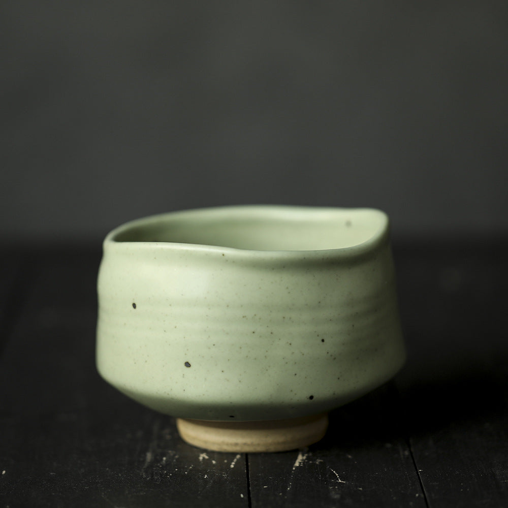 Green ceramic Matcha Bowl on a dark surface with a dark background