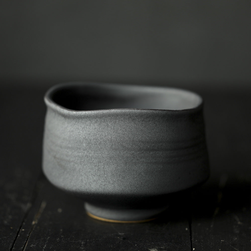Dark ceramic matcha bowl on a dark wooden surface