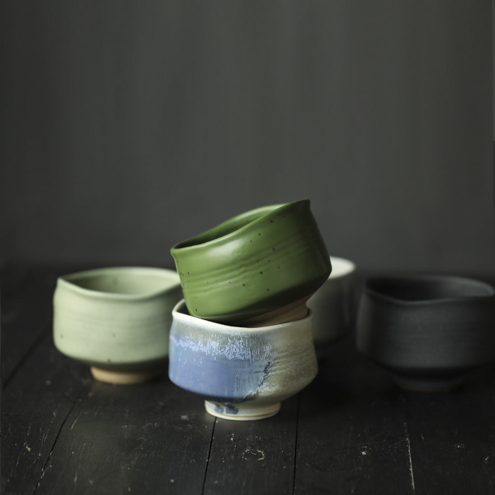 Matcha Bowl in green, blue, and black on a dark wooden surface with a dark background.