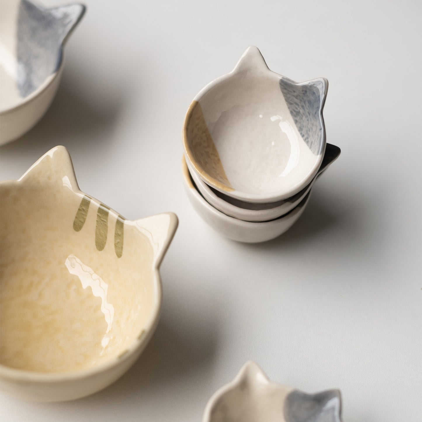 Cream cat ceramic bowls stacked, with a ginger cat-head bowl in front
