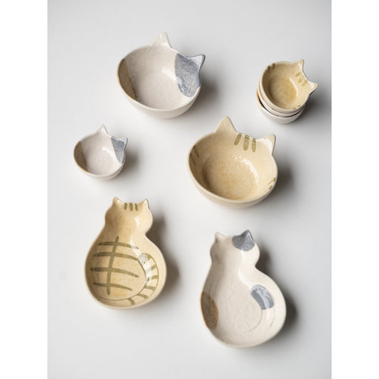 Cream cat ceramic dishes, the full set of shapes in calico and ginger on a white table