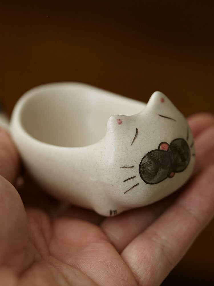 Sleepy cat chopstick rest dish held in a hand, showing the belly hollow and painted face