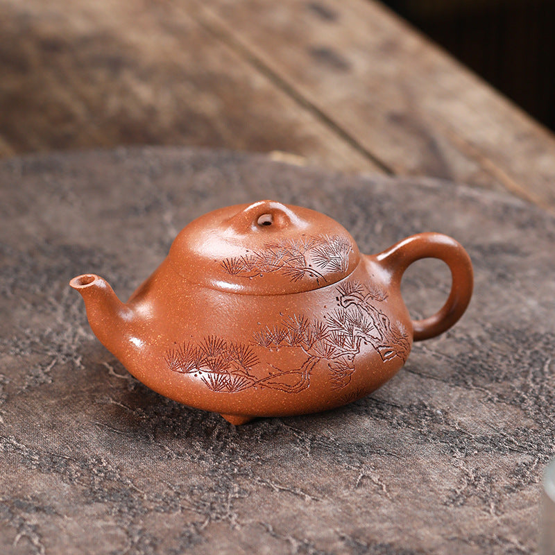 Pine Wind Yixing teapot in Jiangpo clay on a stone slab, hand-carved pine branch running across the lid and body