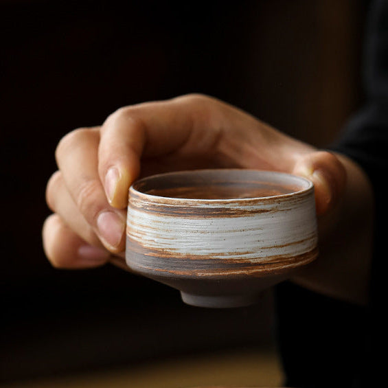 Person holding a ceramic cup with a warm, blurred background