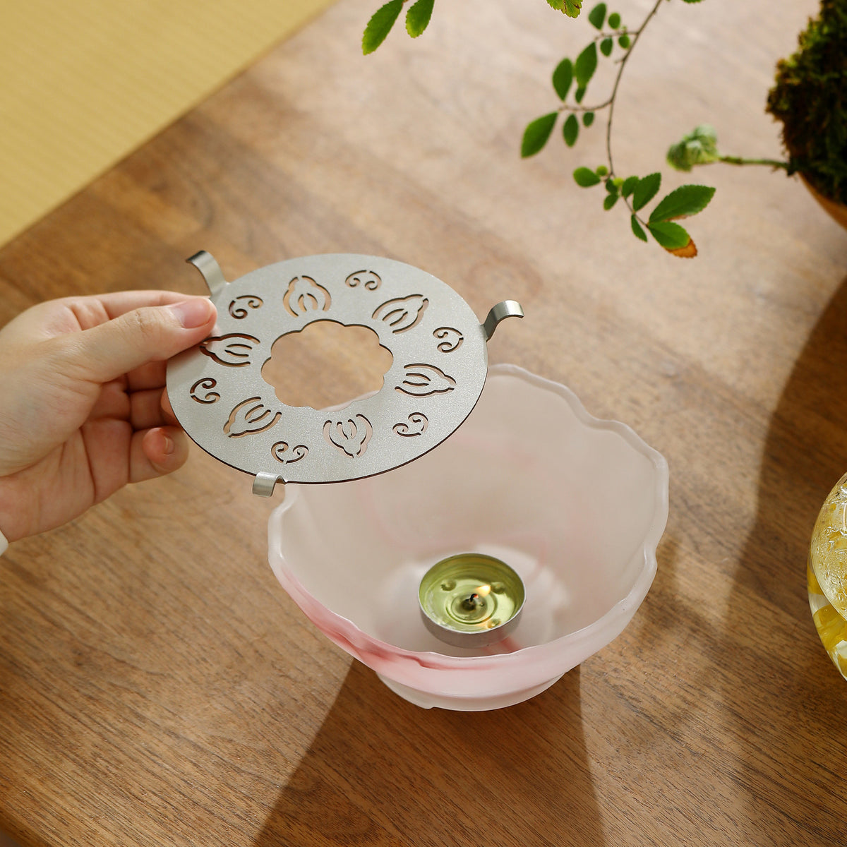 Steel plate lifted off the pink glass tea warmer to show the tealight inside