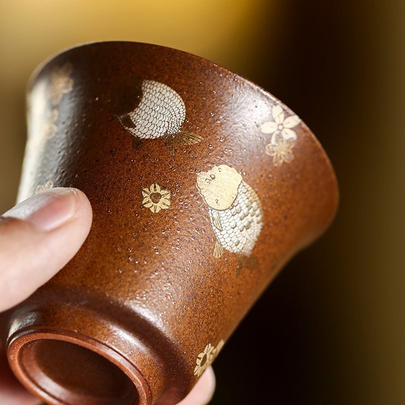 Rock clay tea cup held in hand showing gold and silver fish detail