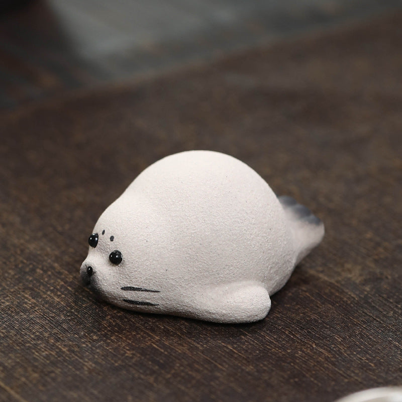 Handmade Yixing duanni clay seal tea pet, white with black eyes and whiskers, on a wood tea table