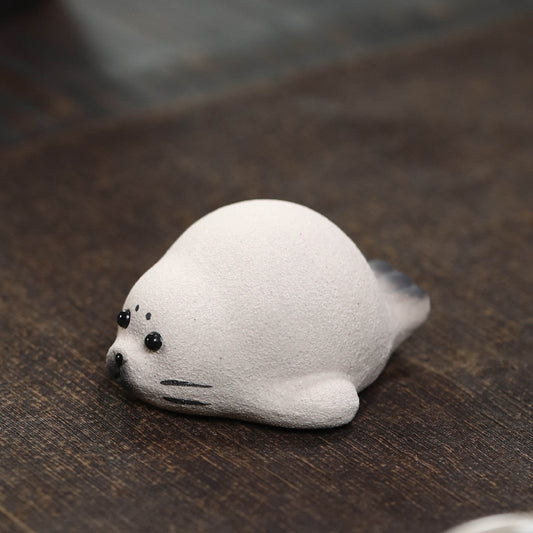 Handmade Yixing duanni clay seal tea pet, white with black eyes and whiskers, on a wood tea table