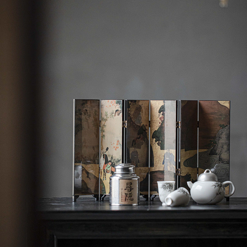 Gold Meadow mini folding screen, reverse mountain scene, standing behind a white teapot, cup and silver tea canister
