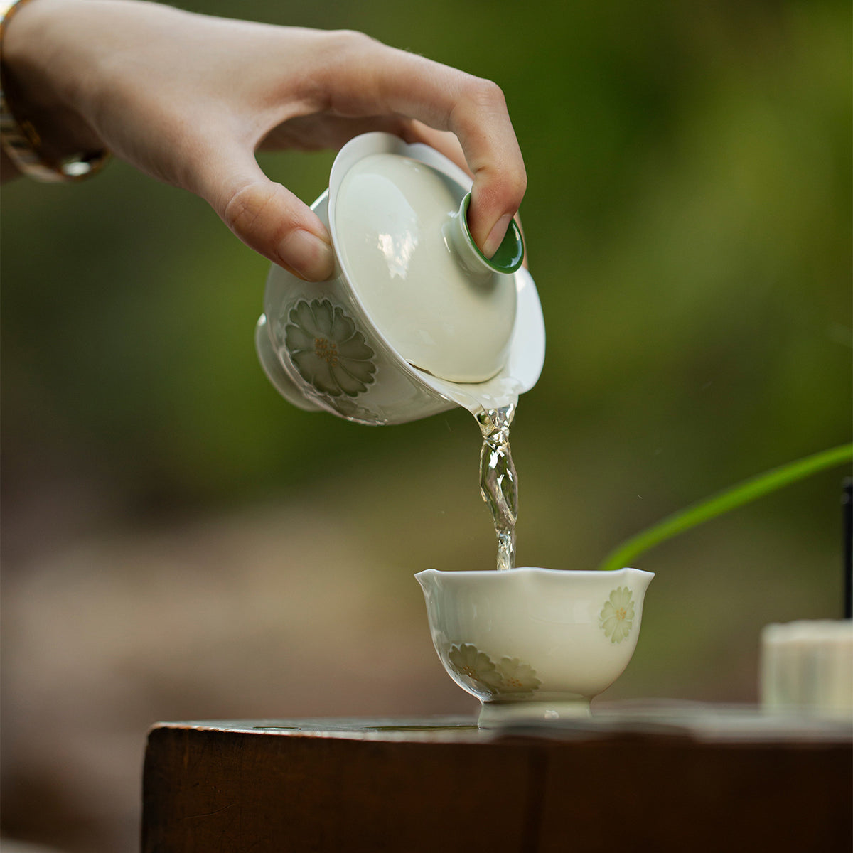 Tea being poured into a chrysanthemum hand-painted porcelain cup