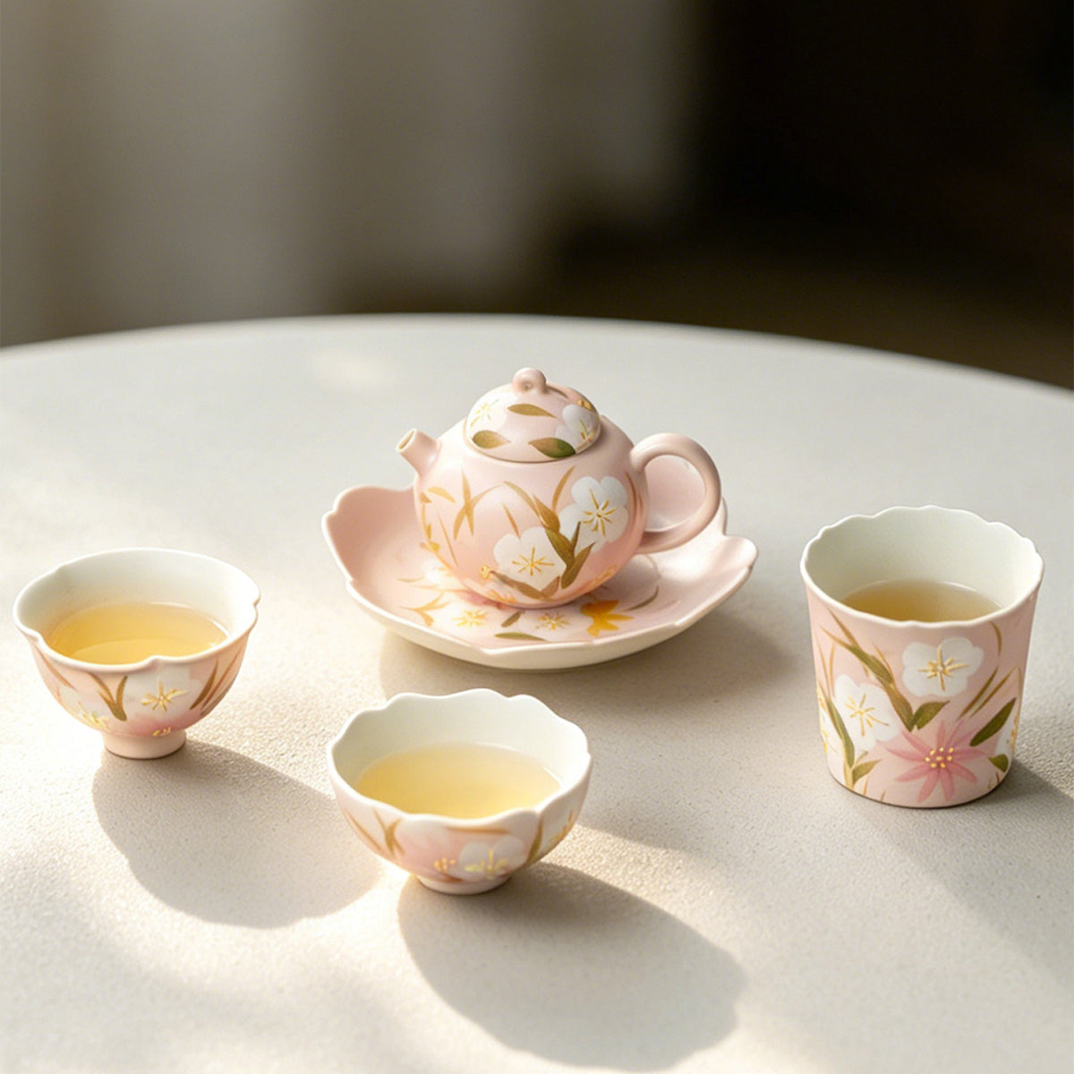 Peach pink wildflower cups filled with tea beside the teapot