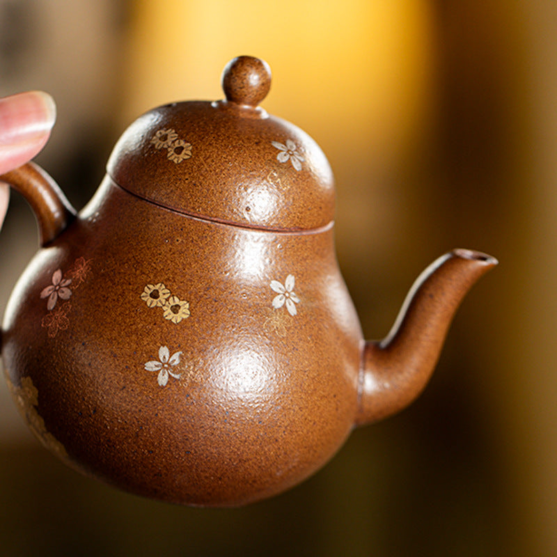 Close-up of the gold and silver fish and blossoms on the rock clay teapot