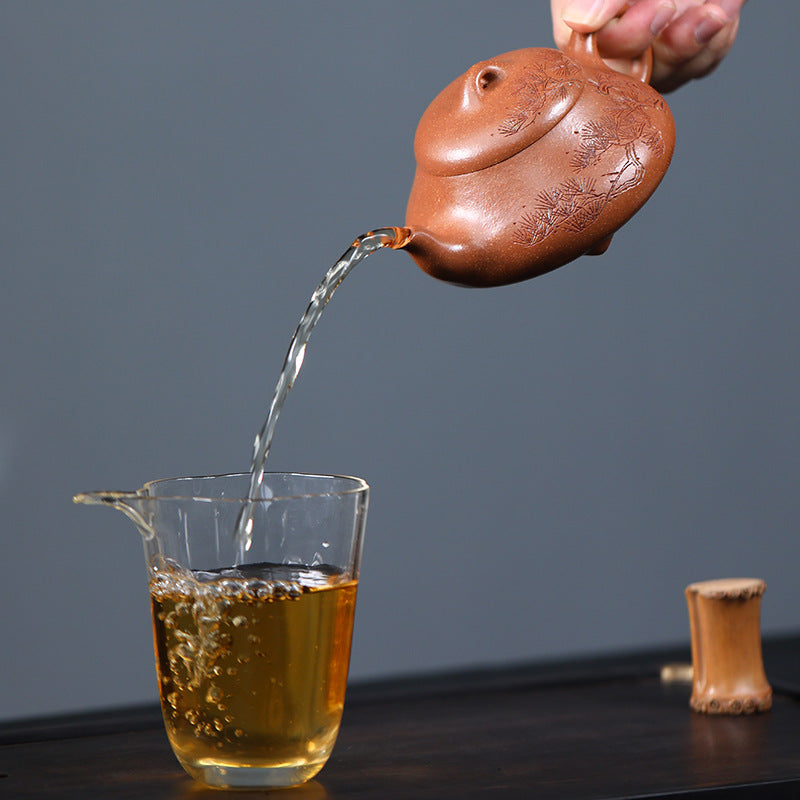 Pine Wind Yixing teapot pouring a clear amber stream into a glass fair cup