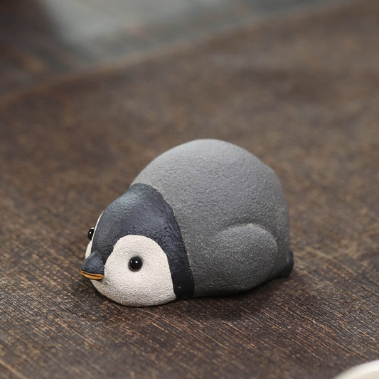Handmade Yixing duanni clay penguin tea pet on a dark wood tea table